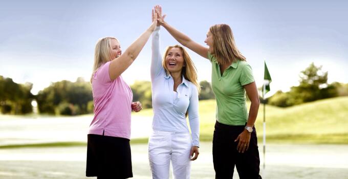 Women On Course Three Ladies Hi Five Having with friends on the golf course.