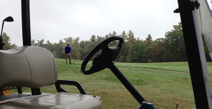 Golfer watching his drive with golf cart in foreground Golfer watching his drive with golf cart in foreground